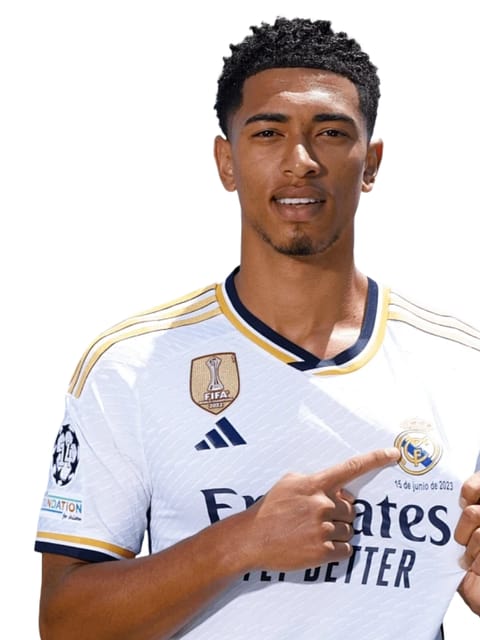 Retrato de Jude Bellingham com short afro preto, vestindo uma camisa branca do Real Madrid. Ele tem um dos dedos indicadores apontando para o logotipo do Madrid, contra um fundo branco liso.