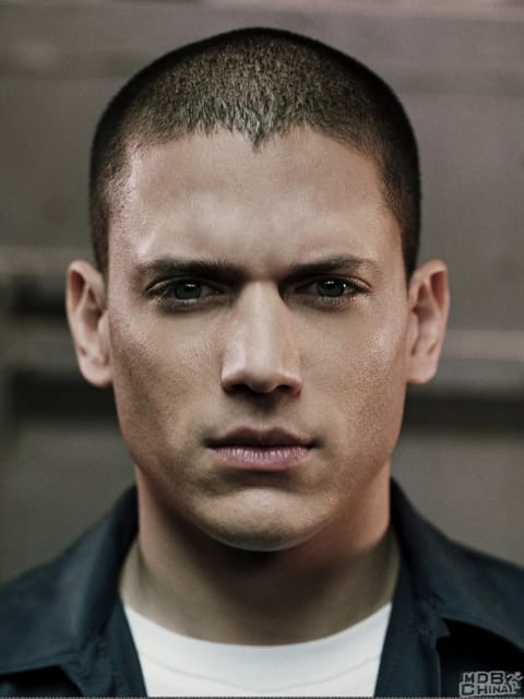 Close de Wentworth Miller com corte curto e expressão intensa e séria. Ele usa blazer preto combinado com top branco. Modelo para troca de rosto de imagem.