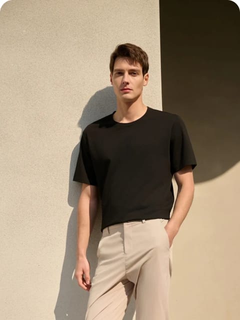 Un hombre con camiseta negra y pantalones beige, de pie al aire libre, modelo para el intercambio de ropa de IA.