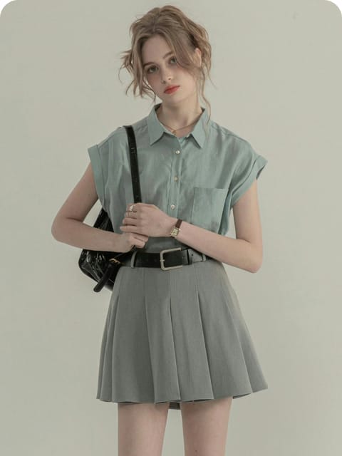 Una mujer con una camisa de manga corta azul claro y una falda plisada gris, con un bolso negro y zapatos negros, modelo para el intercambio de ropa de AI.