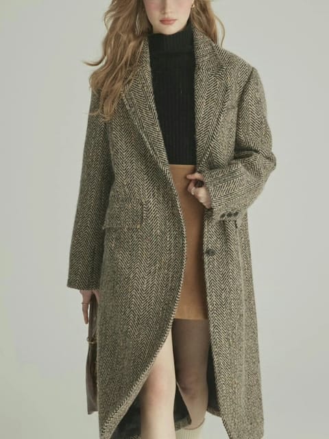 Una mujer con un abrigo largo gris y un jersey de cuello alto negro, con zapatos marrones, modelo para el intercambio de ropa de AI.