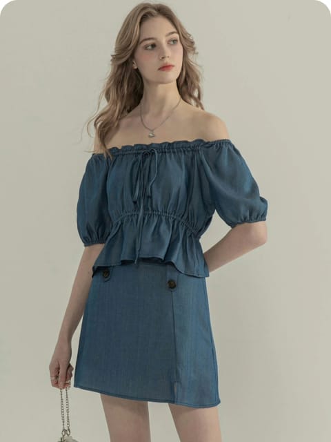 Una mujer con un top azul con hombros descubiertos y una falda a juego, con un pequeño bolso gris, modelo para el intercambio de ropa de AI.