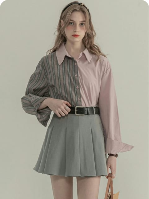 Una mujer con una camisa gris y rosa y una falda plisada gris, con un bolso marrón, modelo para el intercambio de ropa de AI.