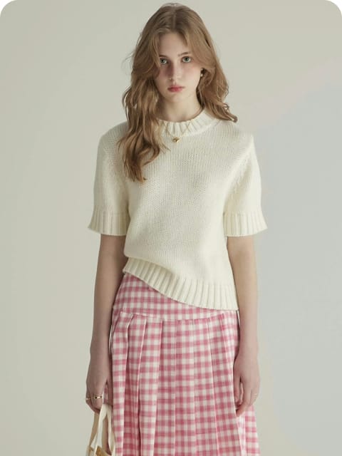 Una mujer con un top de punto blanco y una falda a cuadros rosa, sosteniendo un bolso blanco, modelo para el intercambio de ropa de AI.