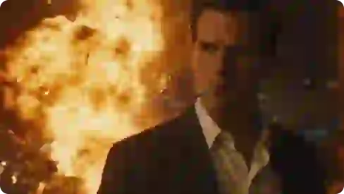 Foto seorang pria dengan rokok di mulutnya, berdiri di depan ledakan besar.