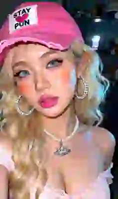 Selfie of a woman with wavy blonde hair, blue eyes, Korean-style matte makeup, a pink beret, silver rhinestone hoop earrings, a pearl necklace, and an off-the-shoulder pink top. Template for an image-to-image tool.