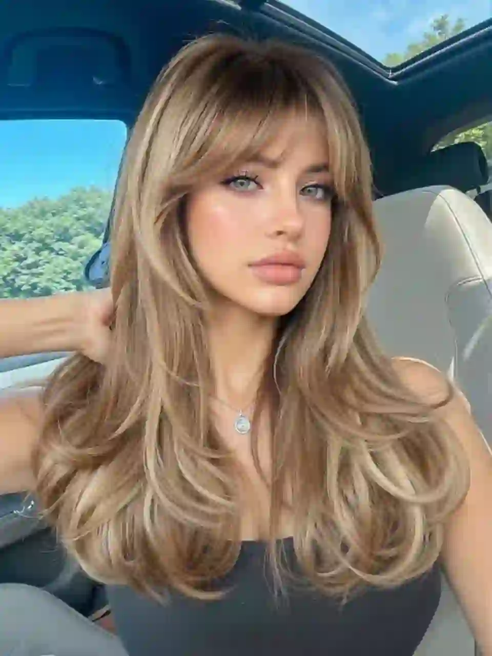 Selfie d'une femme aux cheveux blonds en débardeur gris posant dans une voiture. Modèle pour l'échange de visage d'image.