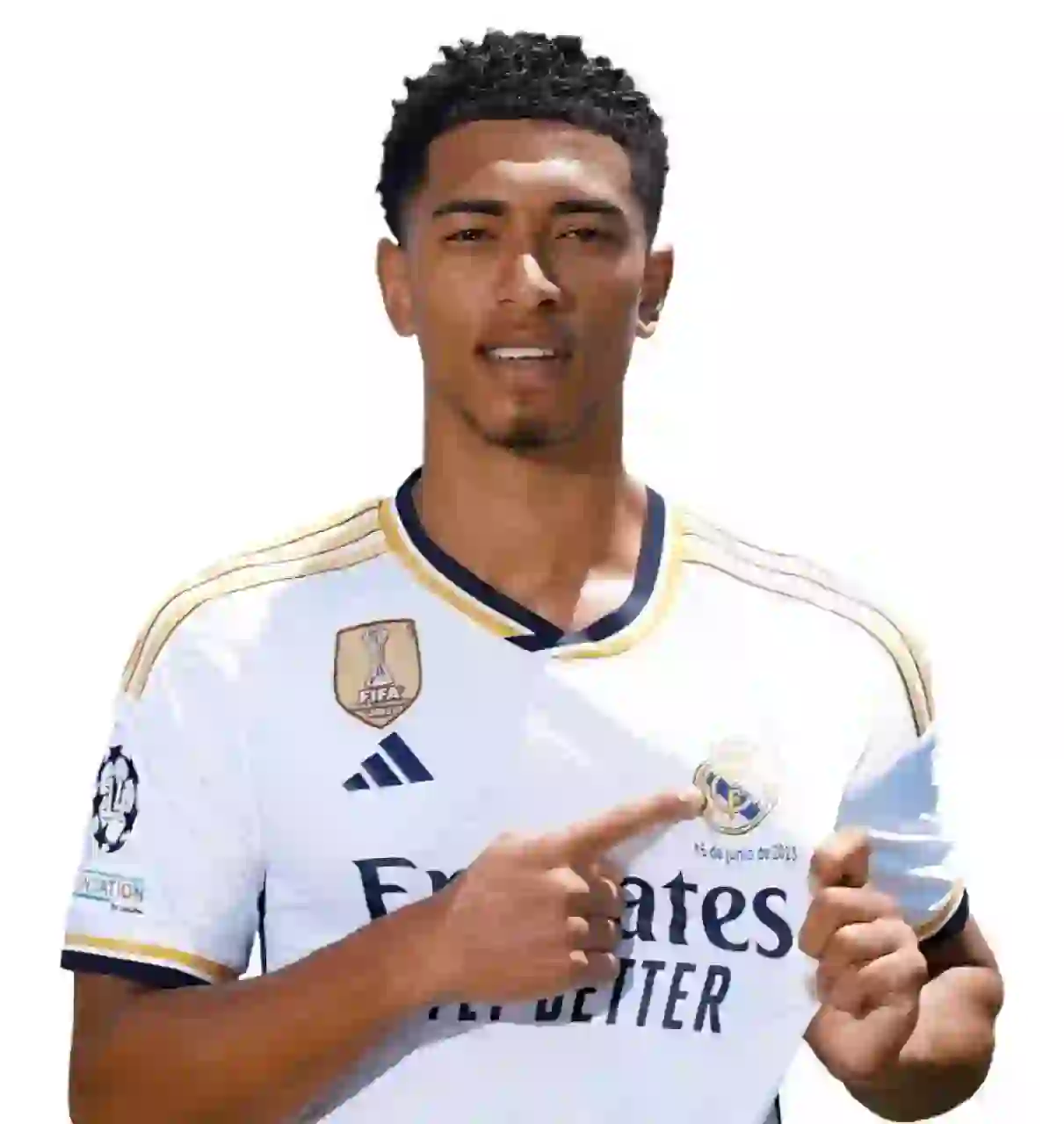 Porträtt av Jude Bellingham med kort svart afro, iklädd en vit Real Madrid hemmatröja. Han har ett av sina pekfinger som pekar mot Madrids logotyp, mot en vanlig vit bakgrund.