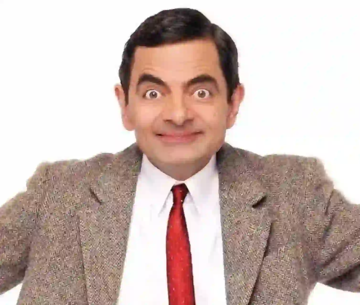 Porträtt av Mr. Bean med slickat hår med ett överdrivet uttryck, klädd i en kakiblazer över en vit skjorta med krage och en röd slips. Hans armar sträcker sig upp mot en vanlig vit bakgrund.