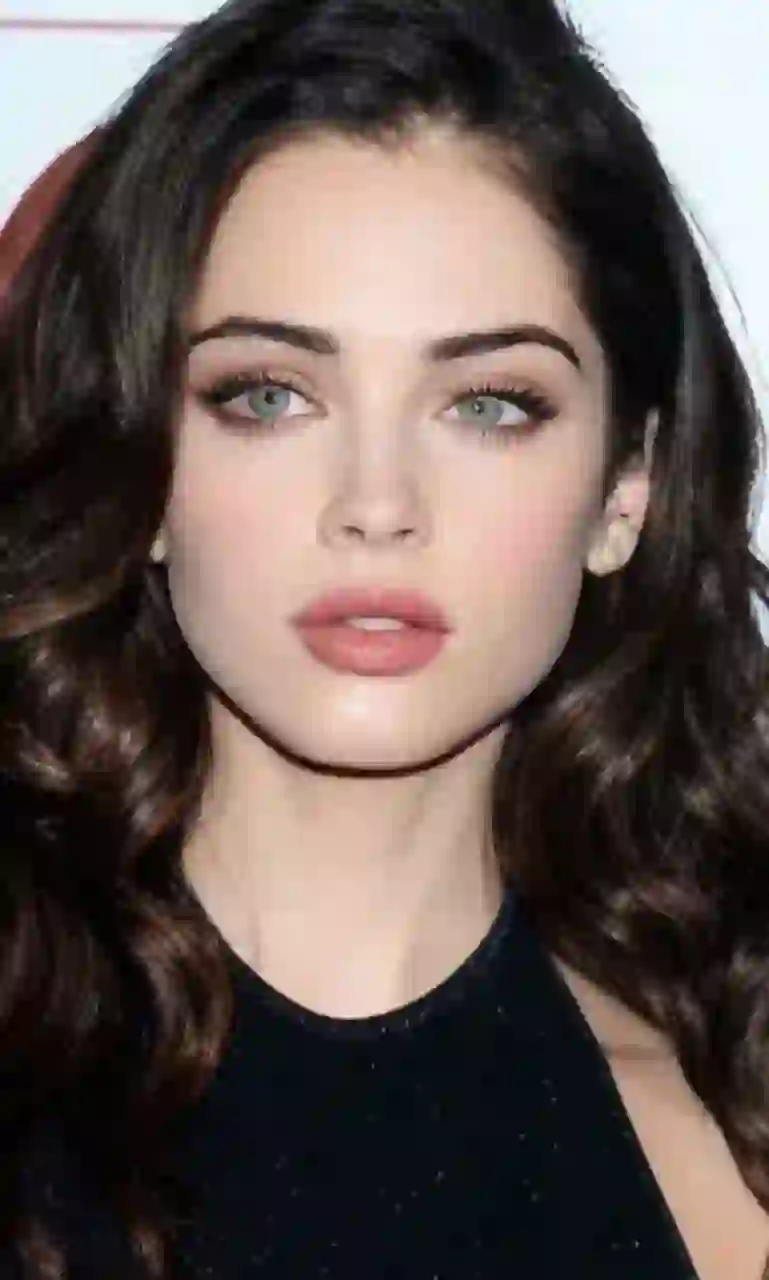 Portrait d'une femme aux cheveux bruns ondulés et aux yeux verts, en robe noire sans manches. Modèle pour l'échange de visage d'image.