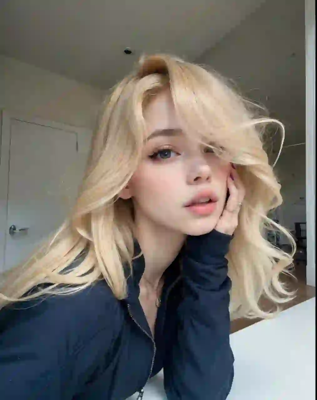 Selfie d'une femme aux cheveux blonds ondulés en blazer bleu foncé posant dans une scène intérieure. Modèle pour l'échange de visage d'image.