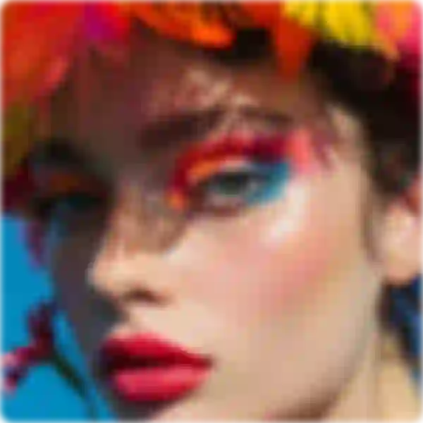 Mavi ve turuncu göz farı, kırmızı ruj ve çok renkli tüylü başlık içeren bir kadının bulanık fotoğrafı.