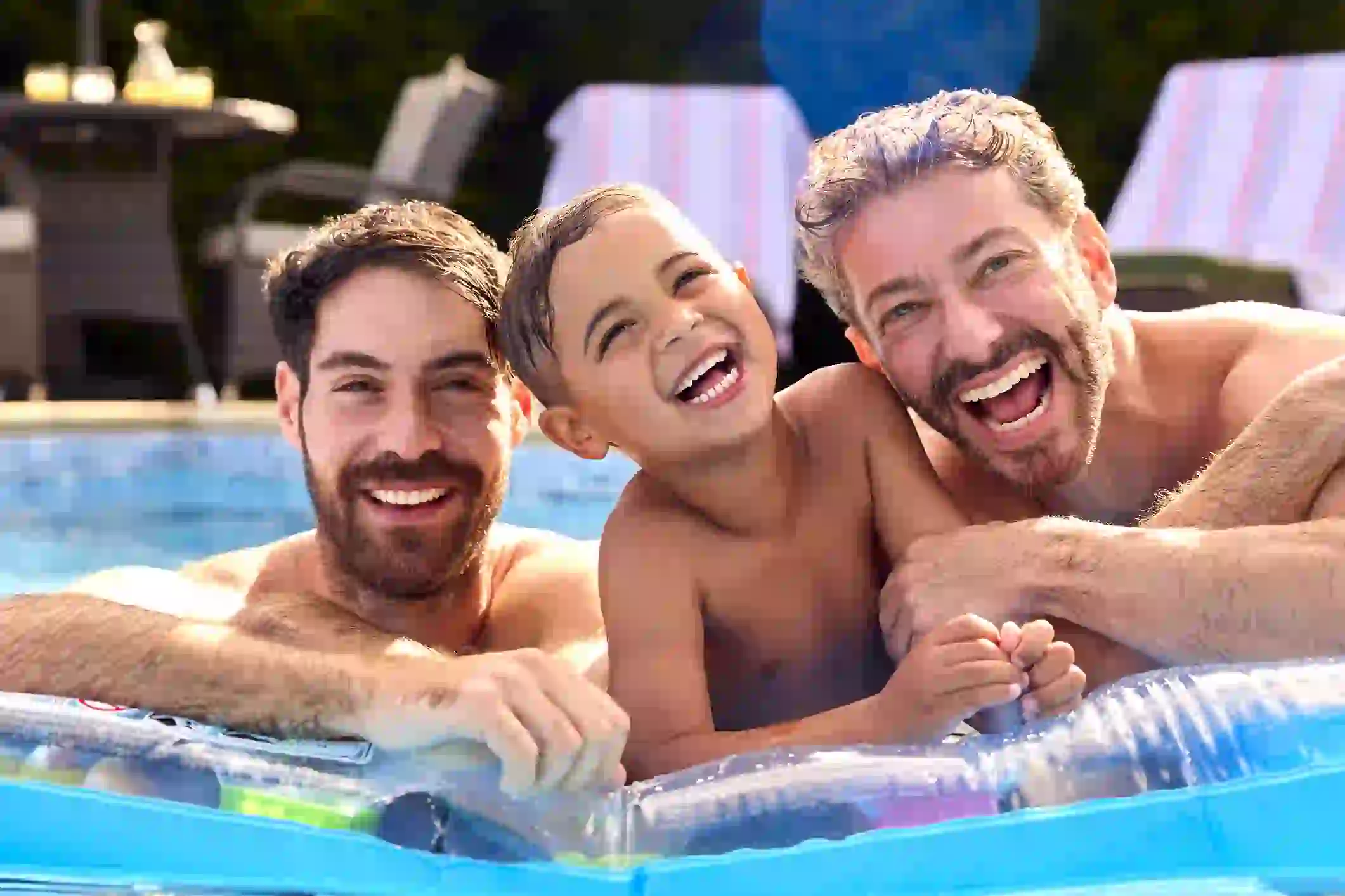 This is a screenshot of an American gay dad couple with their child playing in the pool. This is how they look before the multiple face swap video.