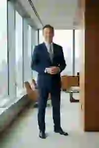 Hình ảnh do AI tạo ra về một người đàn ông đang mỉm cười trong bộ vest sọc xanh đậm đứng trong văn phòng sang trọng, nhìn ra thành phố bên ngoài cửa sổ. Mẫu cho trình tạo ký tự South Park.