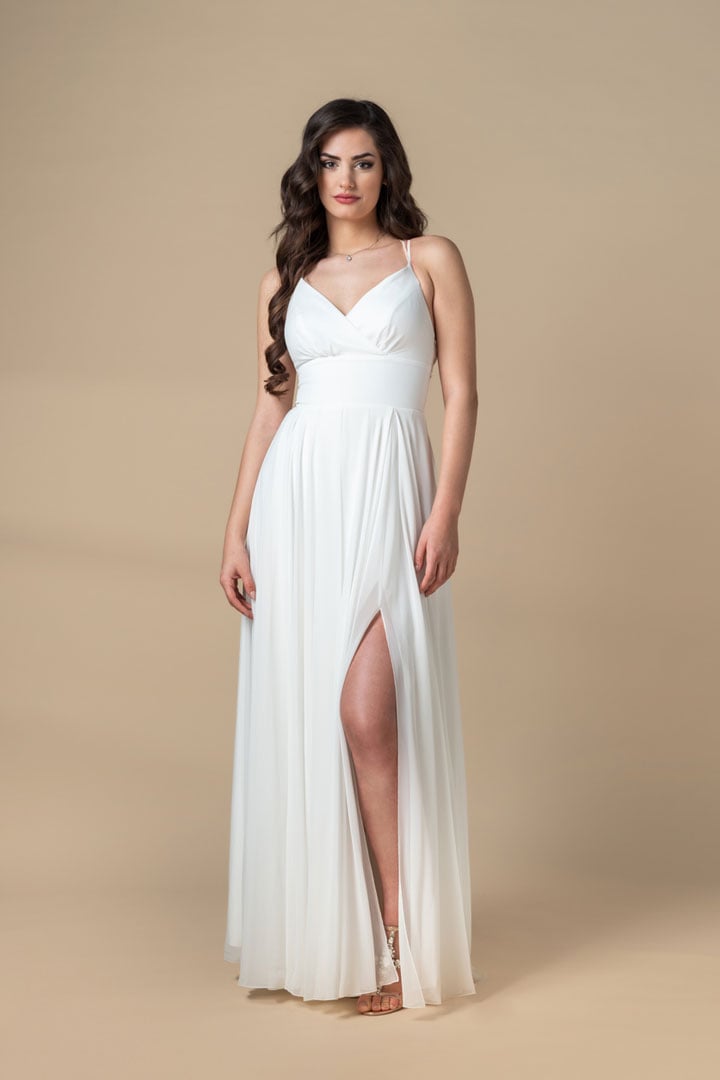 Una elegante mujer blanca se encuentra con un vestido blanco. Ella está lista para un intercambio de ropa. Haga clic para cambiar su ropa con AI.
