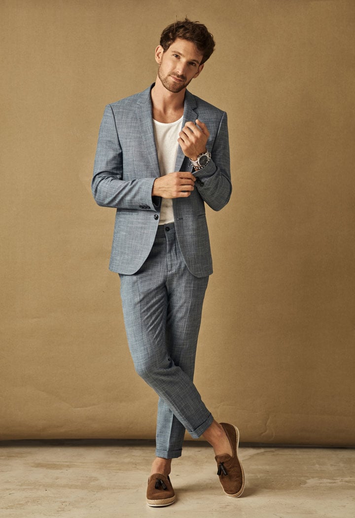 Una foto de cuerpo completo de una modelo de intercambio de ropa, vestida con un traje gris, que muestra cómo cambiar la ropa.