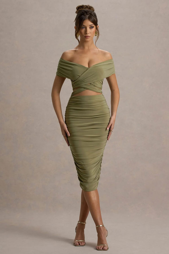 Una foto de cuerpo completo de una ropa de ropa caliente, vestida con un vestido verde, que muestra cómo cambiar la ropa.