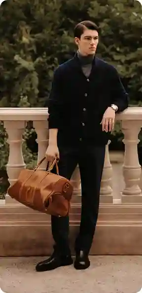 En mand i en sort cardigan og bukser, med en brun taske i hånden, i en have, model for AI-tøjbytte.